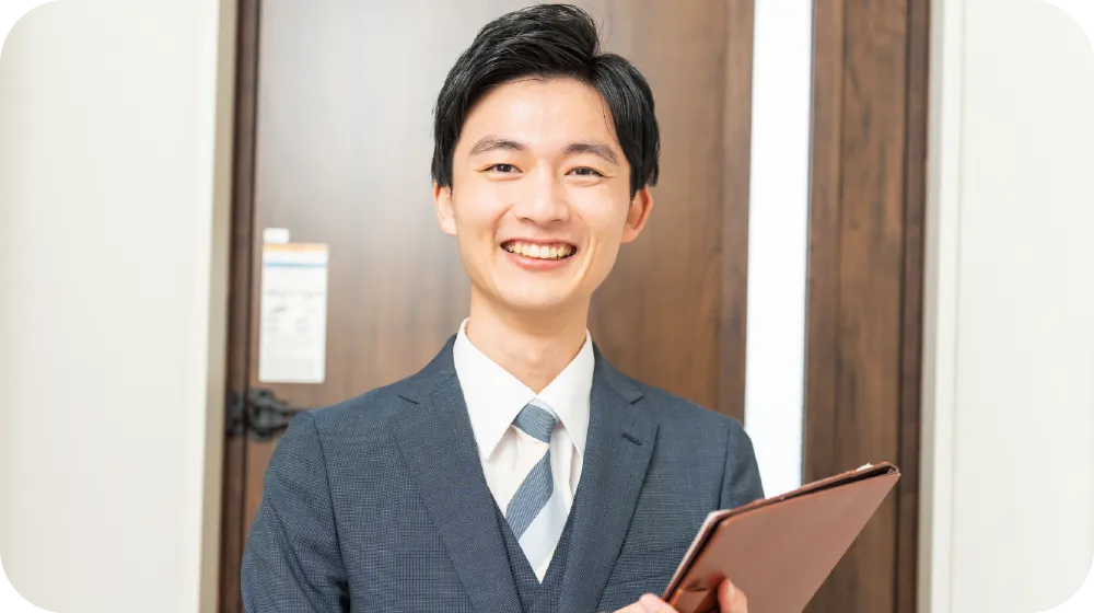 スーツ姿で笑顔の男性スタッフがタブレットを持ち、丁寧に対応している様子。