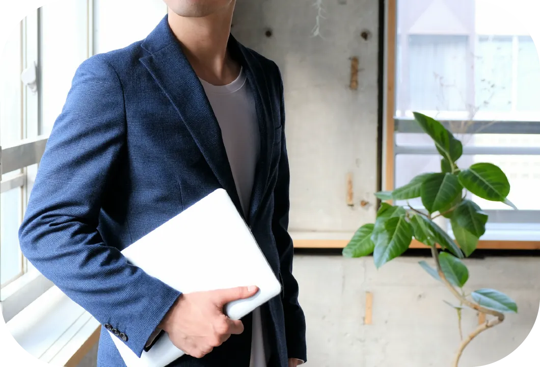 ノートパソコンを持つスーツ姿の男性。